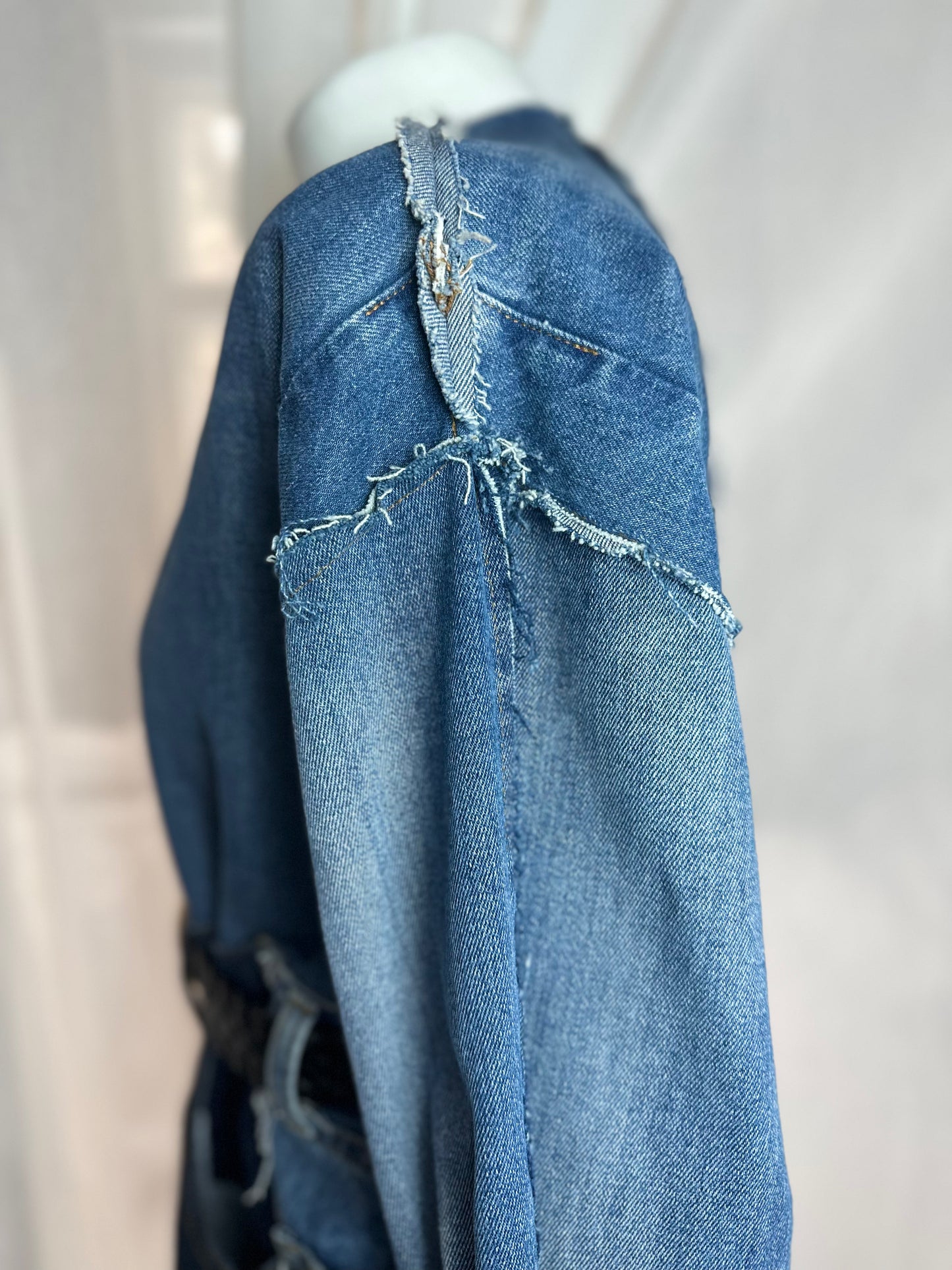 Long upcycled denim coat with frayed seams and macramé belt
