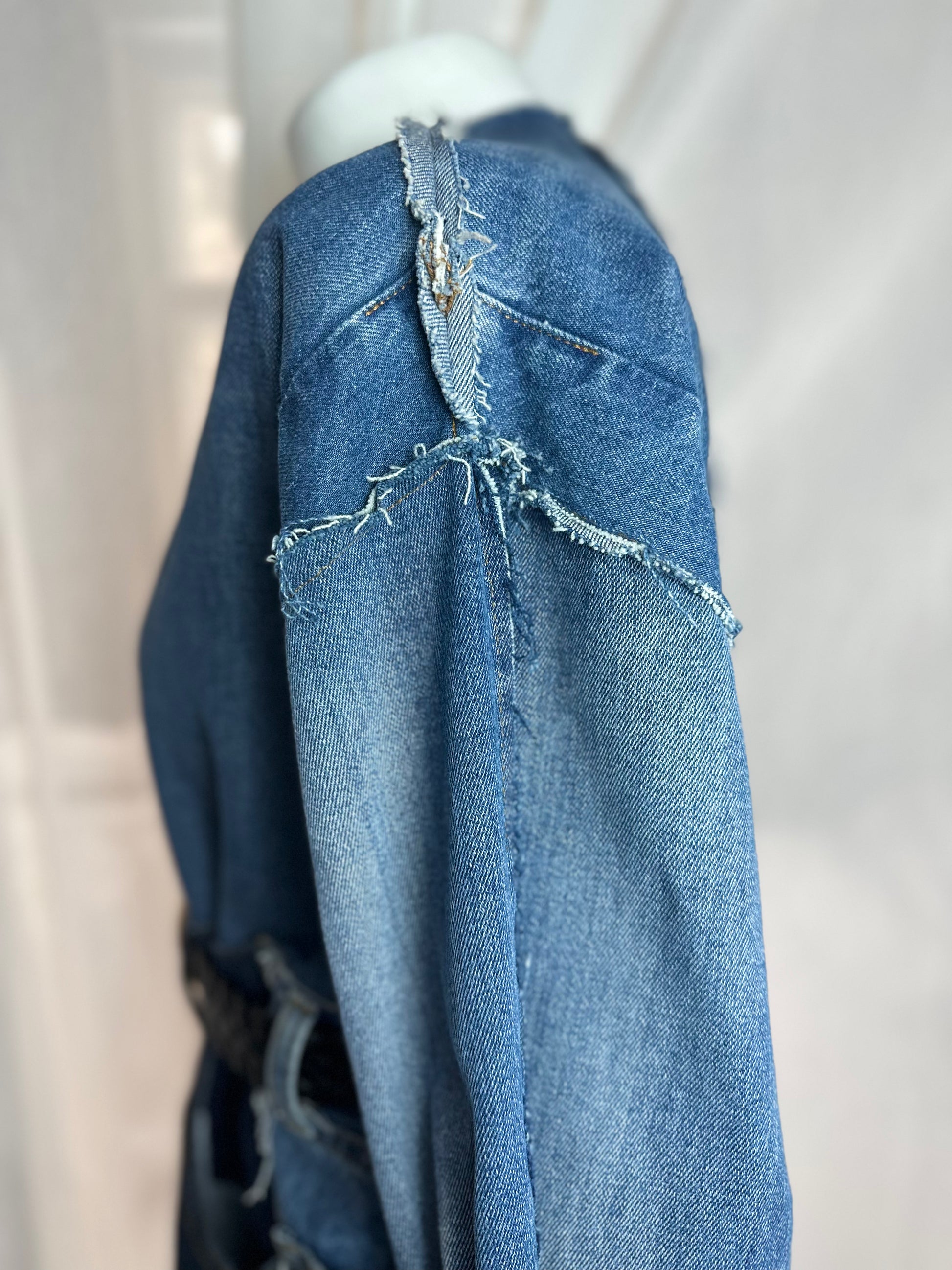 Long upcycled denim coat with frayed seams and macramé belt